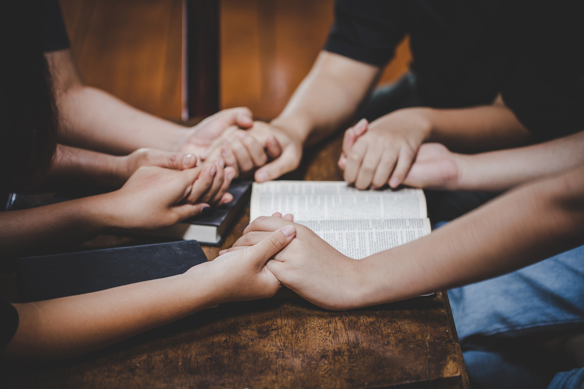 Hands of Individuals Holding for Prayer with Bibles